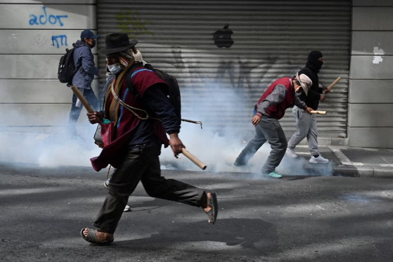 Un manifestante corre mientras los manifestantes chocan con las fuerzas del orden durante una marcha que pide la dimisión del presidente de Bolivia, Rodrigo Paz. La Paz, Bolivia. REUTERS/Claudia Morales