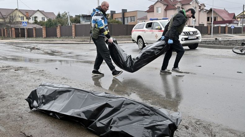 Muerte. Agentes ucranianos recogen dos cuerpos en las calles de Bucha, adonde acudió Zelenski ayer.