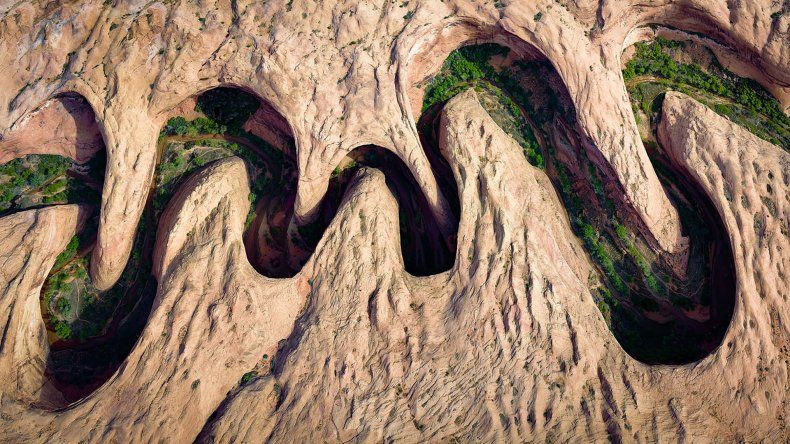 La vegetación verde florece en el borde del río de un cañón serpenteante en Utah.