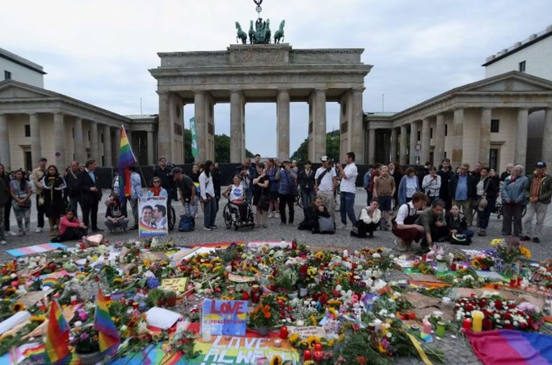 Un grupo de personas homenajes a las víctimas del atropello masivo en la puerta de Brandeburgo, en Berlín