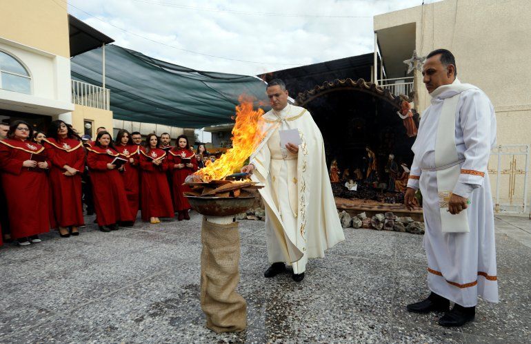 Una sacerdote enciende un fuego durante la misa de Navidad en la Iglesia Caldea de San Jorge en Bagdad, Irak (REUTERS Khalid al Mousily)