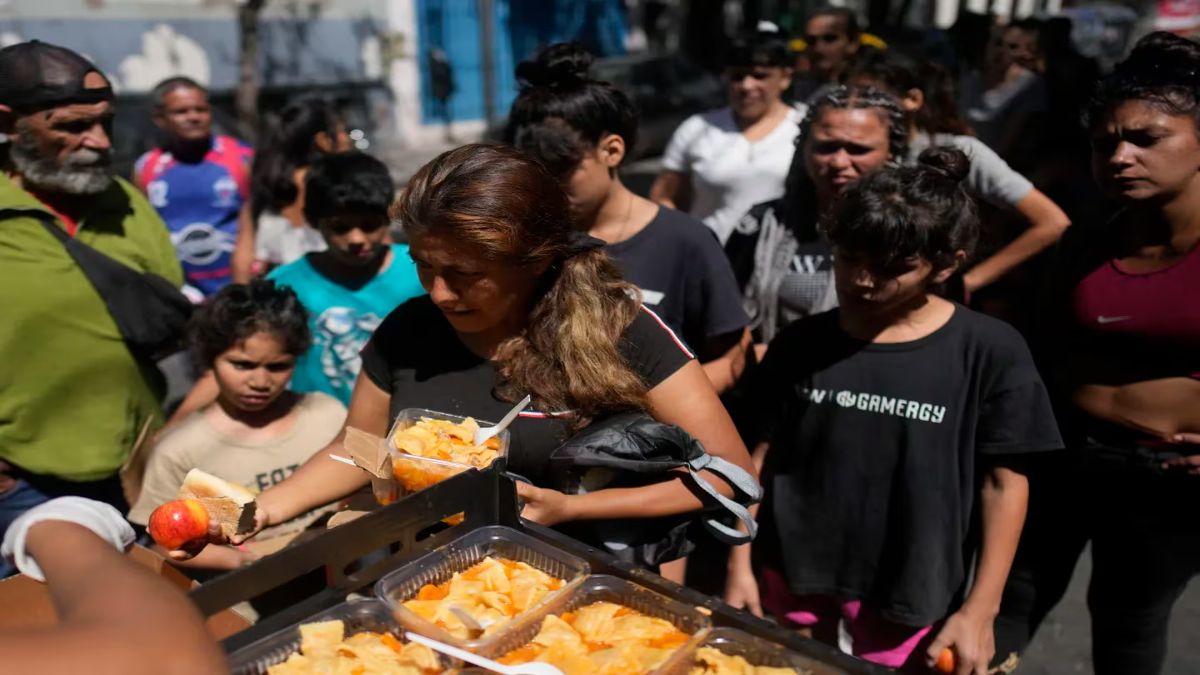 La gente recibe comidas calientes gratuitas en un comedor comunitario dirigido por el Movimiento de Trabajadores Excluidos.