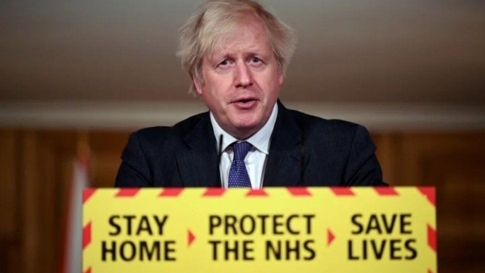 Boris Johnson en Downing St., con carteles llamando a quedarse en casa, proteger al personal de salud y salvar vidas. /Foto: AP