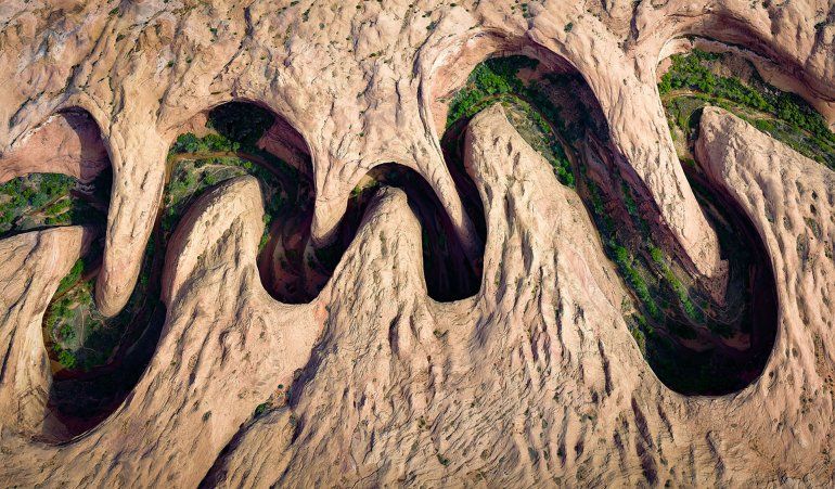 La vegetación verde florece en el borde del río de un cañón serpenteante en Utah.