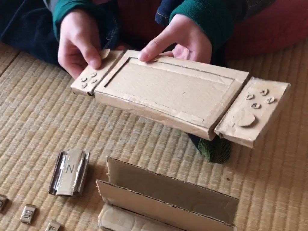 Nene jugando con su consola de cartón