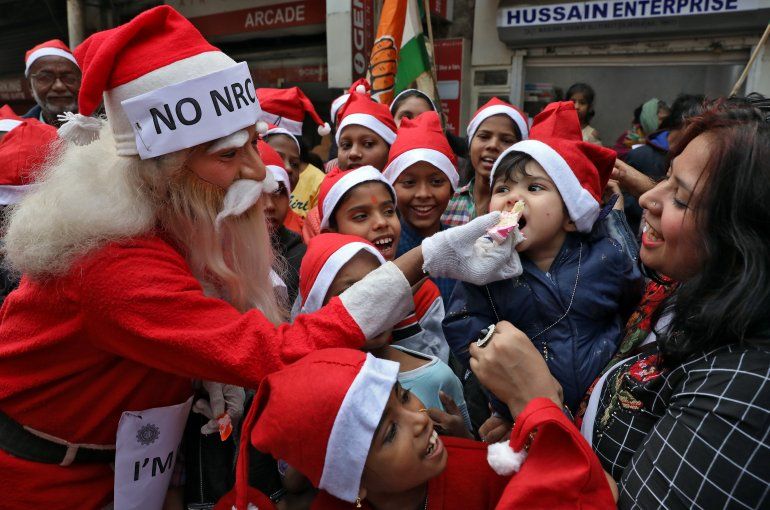 Un hombre vestido de Santa Claus ofrece comida a un ni&ntilde;o en Kolkata, India (REUTERS Rupak De Chowdhuri)