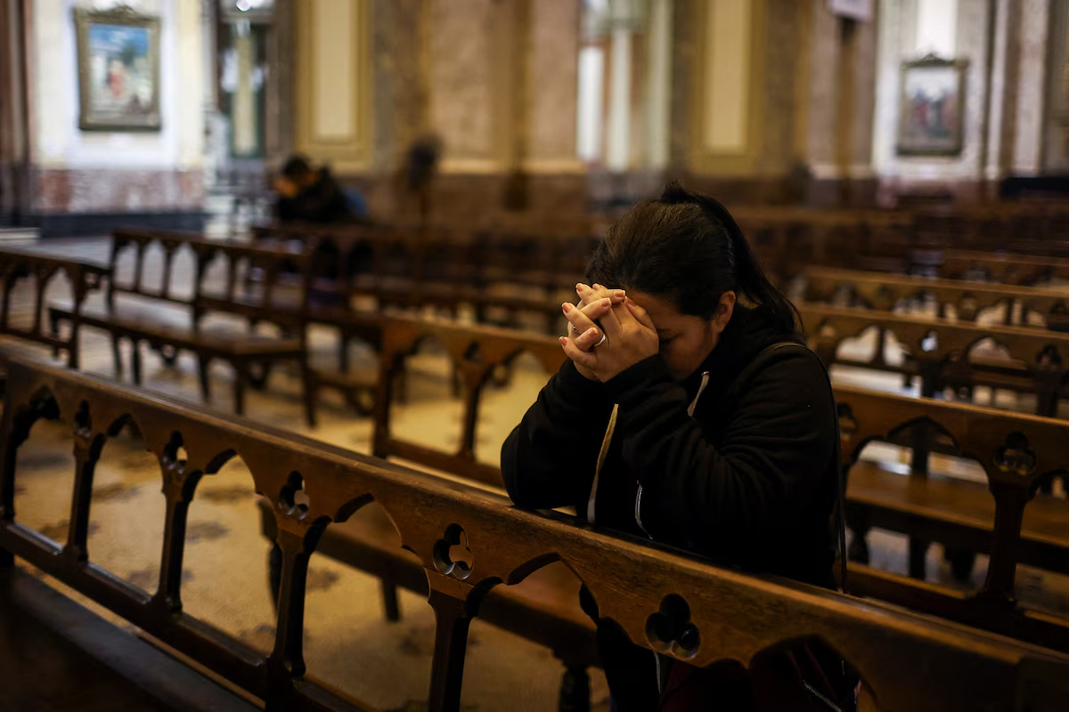 Una mujer reza y llora en una iglesia porteña, donde el papa Francisco vivió hasta los 76 años, cuando fue elegido Papa y debió mudarse al Vaticano (REUTERS/Agustin Marcarian)