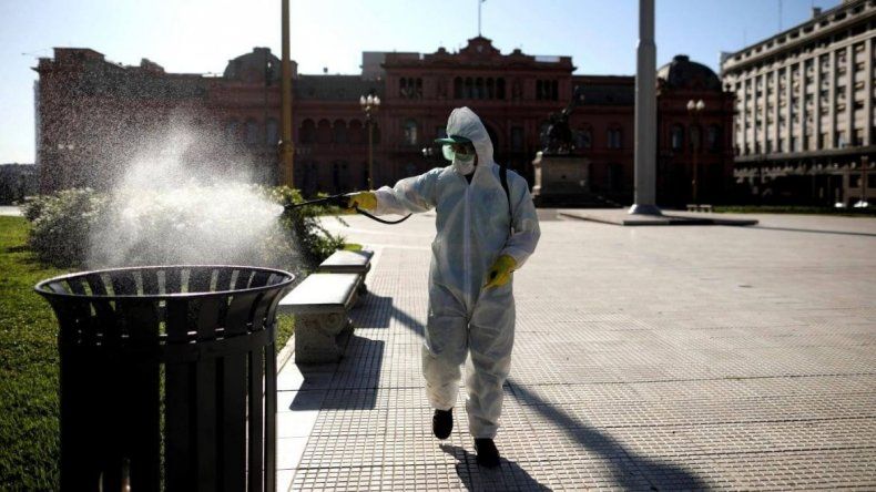 Plaza de Mayo desierta durante la cuarentena, mientras un trabajador desinfecta.