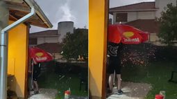 Un joven utiliza sombrilla para proteger el asado durante una tormenta de granizo en Mar del Plata.